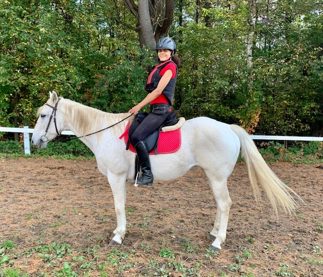 A young woman riding a white horse