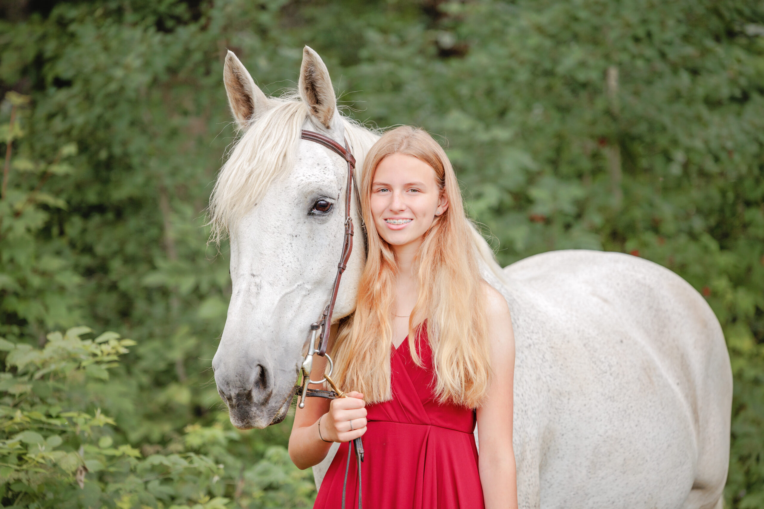 A blonde woman in a red dress with a white horse