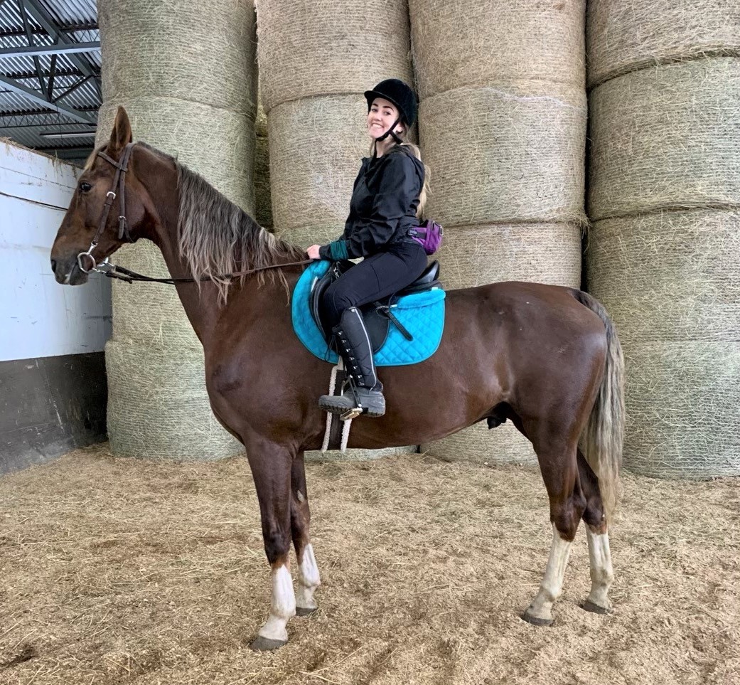 A woman riding a horse inside a barn